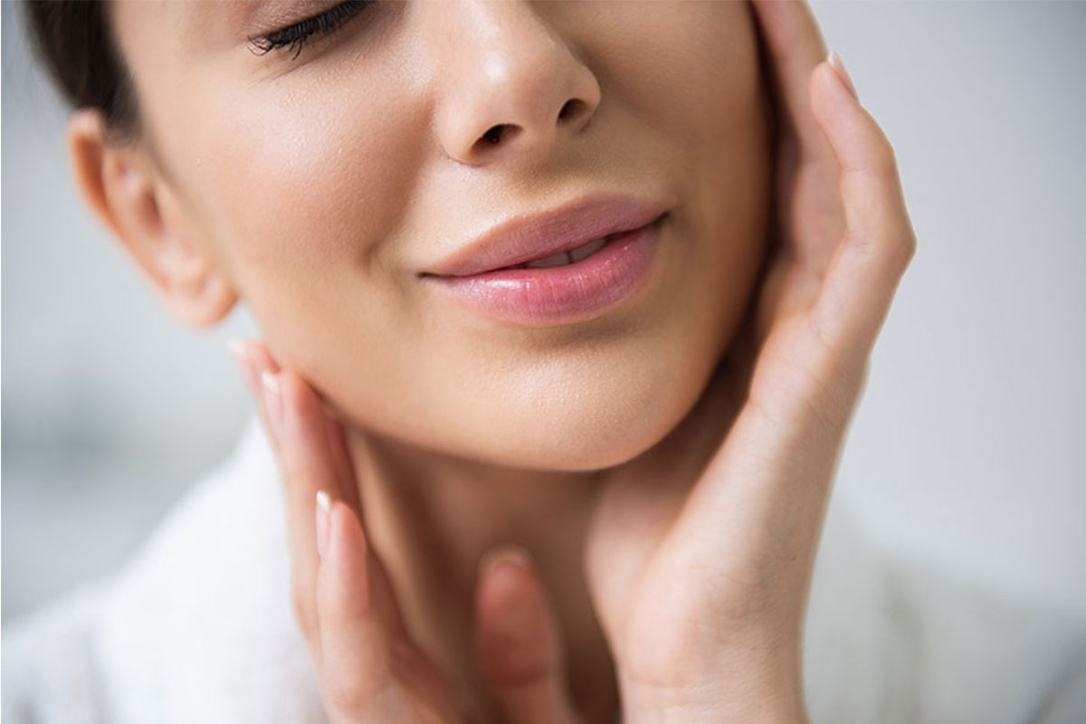 Woman gently touching her face, highlighting smooth and youthful skin
